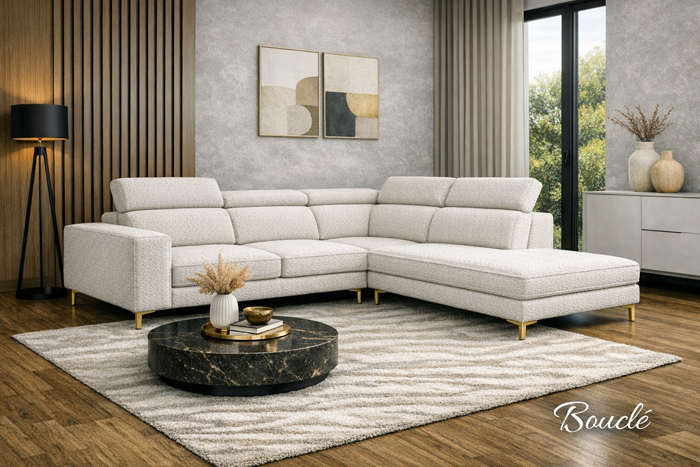 Narożnik tapicerowany jasną tkaniną bouclé o wyrazistej, pętelkowej strukturze, ustawiony w eleganckim salonie z marmurowym stolikiem, drewnianą podłogą i minimalistycznymi dekoracjami.