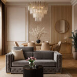 Elegancki salon z szarą sofą M125 z weluru, ustawioną przy okrągłym stoliku kawowym, z widokiem na jadalnię z drewnianym stołem i żyrandolem.