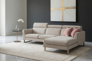 Narożnik M136 firmy Mebel Akimo w jasnej tkaninie, ustawiony w nowoczesnym salonie z ciemną ścianą i złotymi akcentami.